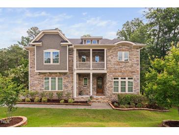 Stunning stone-clad two-story home featuring a second-story balcony and a beautifully landscaped front yard at 728 Peninsula Forest Pl, Cary, NC 27519
