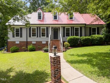 Charming home with red metal roof, black shutters, manicured lawn, and inviting walkway at 101 Joel Ct, Cary, NC 27513