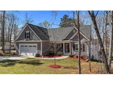Charming gray home boasts a manicured lawn, an attached two-car garage, and a quaint front porch at 1013 Sagamore Dr, Louisburg, NC 27549