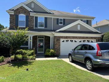 Charming two-story home with stone accents, attached garage, well-kept lawn, and car parked in the driveway at 1831 Devonridge Dr, Fuquay Varina, NC 27526