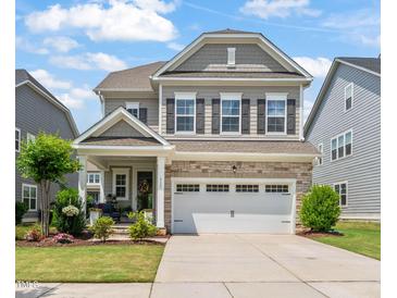 Charming two-story home with stone accents, a well-manicured lawn, and a two car garage at 212 Golf Vista Trl, Holly Springs, NC 27540