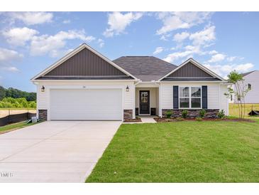 Charming single-story home featuring a two-car garage, manicured lawn, and stone accents at 30 Chloe Ct, Selma, NC 27576