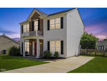 Charming two-story home features a red door, brick accents, a small balcony, and a well-maintained lawn at 3101 Riverbrooke Dr, Raleigh, NC 27610