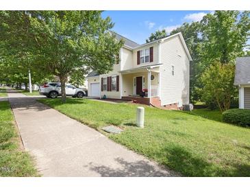 Charming two-story home with a well-manicured lawn, front-facing garage and a cozy front porch at 401 Holly Thorn Trce, Holly Springs, NC 27540