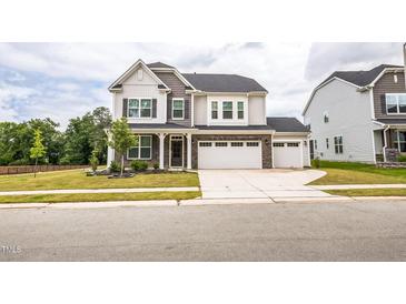 Charming two-story home with stone accents, a three-car garage, and a well-manicured lawn at 1051 Jura Ridge Dr, Fuquay Varina, NC 27526