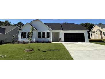 Charming one-story home with a well-manicured lawn, black garage door, and complementary landscaping at 128 Oakfield Trace Dr, Four Oaks, NC 27524