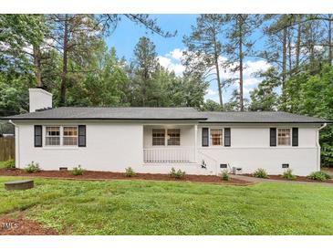 Charming single-story home with a white painted brick exterior, black shutters and a well-manicured lawn at 1523 Oak Forest Dr, Hillsborough, NC 27278
