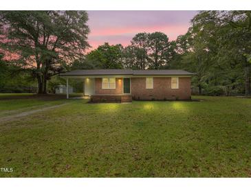 Charming brick home featuring a spacious front yard, complemented by mature trees and a welcoming facade at 658 Love Grove Church Rd, Sanford, NC 27332