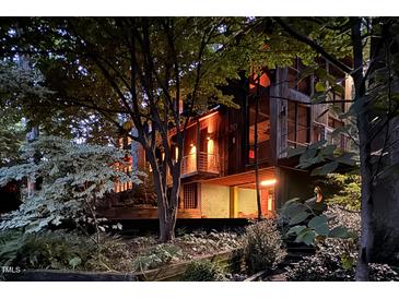 Charming exterior view of home with wood accents and lush landscaping at night at 820 Runnymede Rd Rd, Raleigh, NC 27607