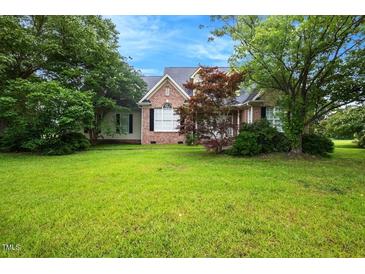 Charming brick home with a lush green lawn and mature trees, offering a serene curb appeal at 1016 Pasture View Ln, Raleigh, NC 27603