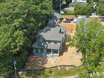 New construction exterior elevation of a blue home with a gray roof surrounded by mature trees and a partially landscaped yard at 1221 Dixie Trl, Raleigh, NC 27607