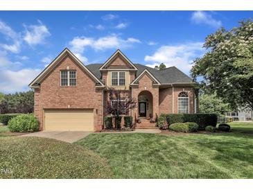 Charming two-story brick home with manicured lawn, arched entry, and attached two-car garage at 12412 Mayhurst Pl, Raleigh, NC 27614