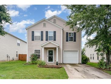 Traditional home featuring a manicured front lawn, mature trees, and attached garage at 4712 Rockport Dr, Durham, NC 27703