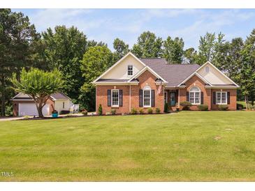 Charming brick home featuring a large lawn, complemented by a two-car garage and an array of mature trees at 6708 Wavcott Dr, Fuquay Varina, NC 27526