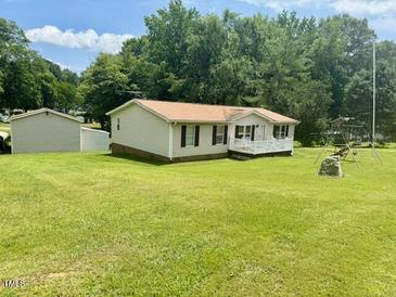 Cozy single-story home with well-maintained lawn, mature trees, and a detached garage at 94 S Waters Edge Ln, Henderson, NC 27537