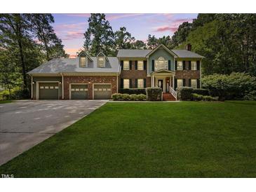 Charming two-story brick home with a three-car garage and landscaped front yard at 1005 Enderbury Dr, Raleigh, NC 27614