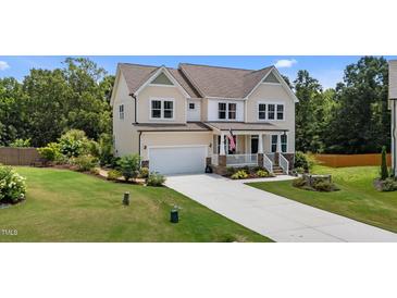 Charming two-story home featuring a manicured lawn, welcoming porch, and attached garage at 185 Twilight Trl, Willow Springs, NC 27592