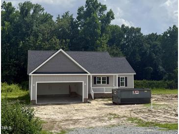 A newly built home with a gray exterior, an open garage and a dark roof with some landscaping to be completed at 2776 Rains Mill Rd, Princeton, NC 27569