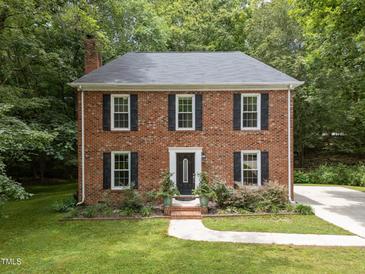 Charming brick home featuring black shutters, a well-manicured lawn, and mature trees offering natural shade at 308 Trappers Sack Rd, Cary, NC 27513