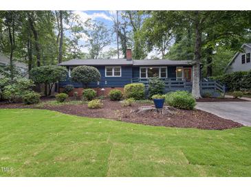 Charming blue home featuring a well-manicured lawn, mature trees and welcoming front entrance at 418 Ridgefield Rd, Chapel Hill, NC 27517