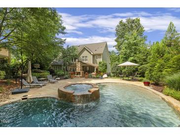 Backyard pool and spa with landscaped patio area offers great outdoor living and entertainment space at 4221 Bibleway Ct, Holly Springs, NC 27540