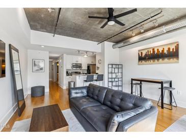Open-concept living area with modern furnishings, concrete ceiling, and hardwood floors at 444 S Blount St # 209, Raleigh, NC 27601