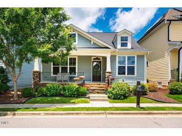 Charming light blue home featuring dormer windows, a cozy front porch, and beautifully landscaped yard at 104 Treywood Ln, Chapel Hill, NC 27516