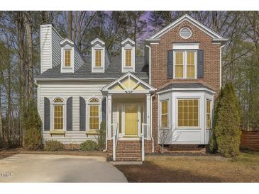 Charming two-story home featuring a mix of brick and siding, dormer windows, and a welcoming yellow front door at 112 Solstice Cir, Cary, NC 27513
