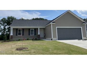 Charming single-story home featuring a covered front porch, attached two-car garage and well-manicured lawn at 116 Oakfield Trace Dr, Four Oaks, NC 27524