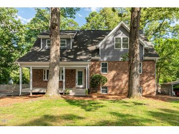 Charming two-story home featuring a brick facade, gray siding, and inviting front porch nestled among mature trees at 205 Northfield Dr, Raleigh, NC 27609