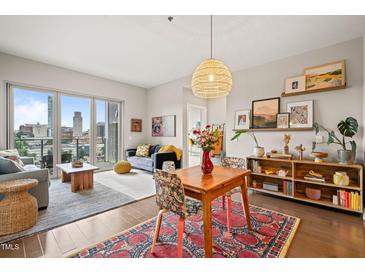 Bright open-concept living room with hardwood floors and a beautiful city view from a private balcony at 214 Hunt St # 701, Durham, NC 27701