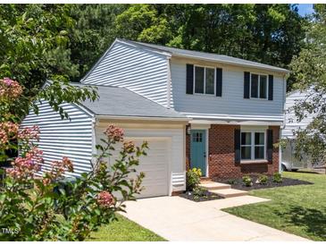 Charming two-story home featuring a brick facade, blue door, landscaped yard, and an attached one car garage at 505 Drolmond Dr, Raleigh, NC 27615