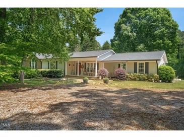 Charming single-story home featuring a welcoming covered porch, complemented by mature trees and beautiful landscaping at 6022 Little Creek Church Rd, Clayton, NC 27520