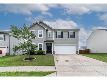 Traditional two-story home with a two-car garage, green lawn, and nicely landscaped yard at 8005 Caithness St, Raleigh, NC 27616