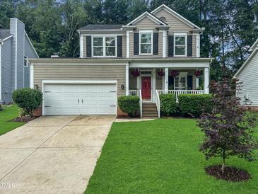 Charming two-story home featuring a manicured lawn, covered porch, and a two-car garage at 8640 Swarthmore Dr, Raleigh, NC 27615