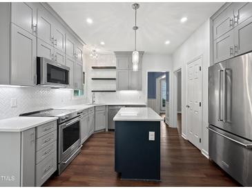 Beautiful kitchen with gray cabinets, stainless appliances, and central island with a white countertop at 8640 Swarthmore Dr, Raleigh, NC 27615