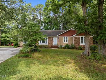Charming single story home featuring well manicured front yard and a brick and wooden exterior at 1040 Ivy Ln, Cary, NC 27511