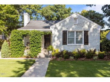 Charming cottage-style home with lush landscaping and a walkway leading to the front door at 1811 Ridley St, Raleigh, NC 27608