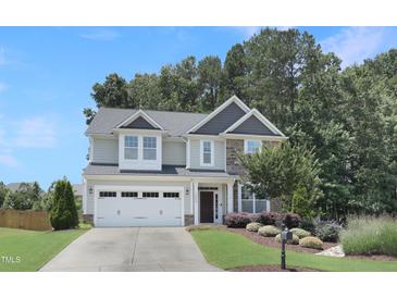 Charming two-story home featuring a manicured lawn, stone accents, and attached two-car garage at 3058 Hyco Lake Ct, Fuquay Varina, NC 27526