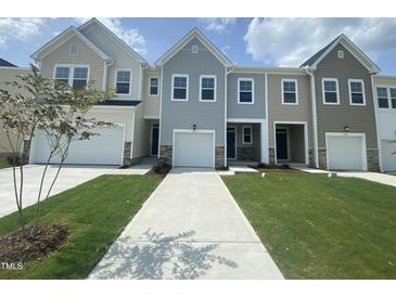 Beautiful townhomes with well-maintained lawns and driveways on a sunny day at 369 Thompson Overlook Way, Smithfield, NC 27577