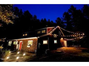 Charming exterior view of a home illuminated with warm string lights at night at 3822 Chicken Bridge Rd, Pittsboro, NC 27312