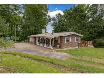 Charming single-story home featuring a cozy front porch and beautiful mature trees at 394 Flanagan Rd, Henderson, NC 27537