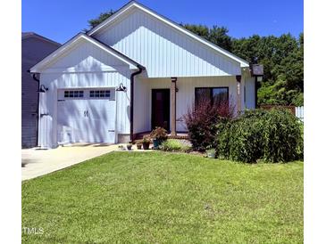 Charming white home with a well-manicured lawn and an attached two-car garage at 451 N Lincoln St, Benson, NC 27504