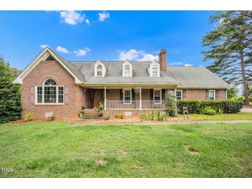 Charming brick home featuring a welcoming front porch, dormer windows, and a well-manicured lawn at 100 Martindale Dr, Youngsville, NC 27596