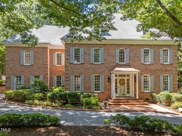 Stately brick home with gray shutters, lush landscaping, and a welcoming brick entryway offers classic curb appeal at 1105 Tazwell Pl, Raleigh, NC 27612