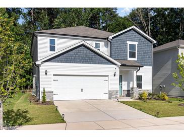 Charming two-story home featuring a 2-car garage, white siding and a welcoming, covered entryway at 1113 Umstead Grove Way, Durham, NC 27712