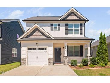 Charming two-story home with a white garage door, stone accents, and a manicured lawn on a sunny day at 147 Sunfish St, Smithfield, NC 27577