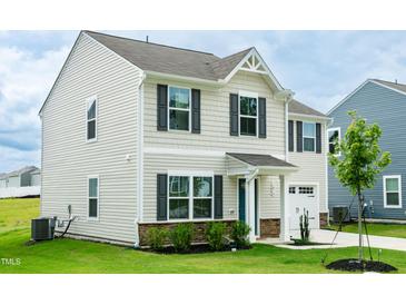 Charming two-story home featuring stone accents, a two-car garage, and a well-maintained lawn at 1476 Burgundy Bluff Ln, Zebulon, NC 27597