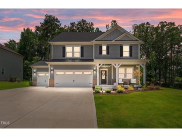 Charming two-story home boasts a three-car garage, welcoming porch, and meticulously landscaped front yard at 165 Hickory Grv Dr, Sanford, NC 27330
