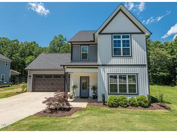 Two-story home with a well-manicured lawn, attached garage, and a welcoming front porch and tidy landscaping at 335 Glenn St, Franklinton, NC 27525